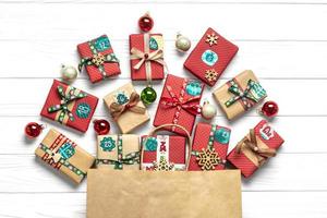 handgemacht verpackte rote, grüne geschenkboxen verziert mit bändern, schneeflocken und zahlen, weihnachtsdekorationen und dekor auf weißem tisch weihnachts-adventskalender-konzept draufsicht flach legen feiertagskarte foto