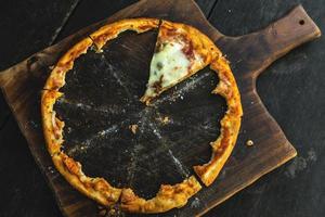 letztes Stück leckere Pizza auf dem Holzbrett foto