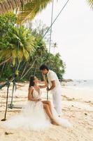 glückliches junges Ehepaar, das seine Hochzeit am Strand feiert foto