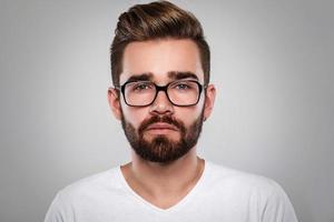 Stilvoller bärtiger Mann mit Brille vor grauem Hintergrund foto