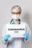 Ärztin hält Papier mit dem Coronavirus-Schriftzug foto