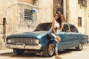 Frau posiert neben altem Auto auf der Straße foto
