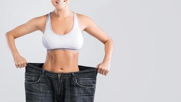 Frau zeigt Ergebnis nach Gewichtsverlust in alten Jeans foto