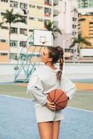 Junge stilvolle Frau posiert auf dem Basketballplatz des Choi Hung Estate foto