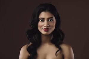 indische Frau mit schönem Make-up und Frisur auf braunem Hintergrund foto