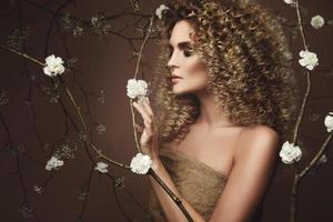 schöne junge frau mit afrofrisur und schönem make-up mit vielen weißen blumen foto