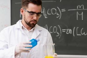 Wissenschaftler, der während der Forschung in einem Labor Wasser in den Becher gießt foto