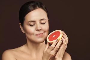 schöne und glückliche Frau mittleren Alters mit einer Grapefruit in der Hand foto