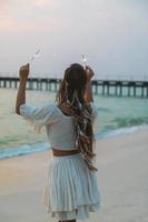 glückliche Frau mit Wunderkerzen am Strand foto