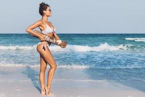 sexy Frau trägt Badeanzug mit alter hölzerner Werbetafel am Strand foto