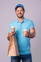 glücklicher lieferbote mit zwei tassen kaffee foto