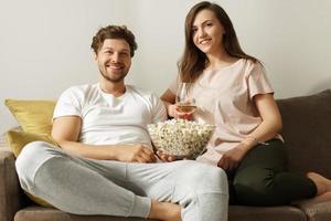 glückliches paar, das wein trinkt und sich zu hause entspannt foto