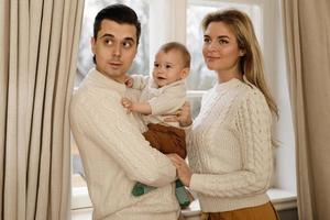 junge und glückliche familie, die neben dem fenster steht foto