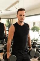 Mann, der während seines Bodybuilding-Trainings im Fitnessstudio mit Hanteln trainiert foto