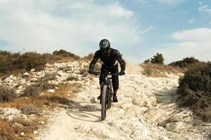 Vollständig mit Schutzausrüstung ausgestatteter Fahrer während der Bergabfahrt auf seinem Fahrrad foto