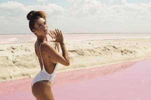 sexy Frau am Strand neben einem rosa Wasser foto