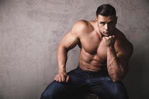 Massiver Bodybuilder posiert neben der Betonwand foto