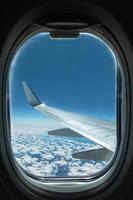 Blick vom Flugzeugfenster auf Flügel und Himmel mit Wolken foto