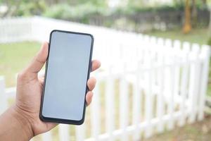 Hand des jungen Mannes mit Smartphone mit grünem Bildschirm gegen Stadtgebäude foto