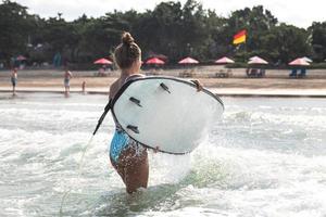 Surferin geht nach ihrem Surftraining vom Meer an die Küste foto