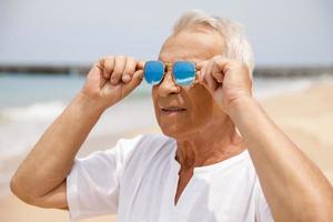 glücklicher älterer Mann, der am Strand spazieren geht foto