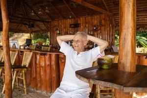 Ein glücklicher Senior trinkt ein Kokoswasser in der Strandbar foto