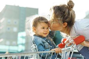 junge schöne mutter und ihr süßer kleiner sohn in einem einkaufswagen foto