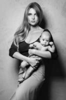 Schöne, gut gekleidete Mutter mit ihrem süßen Baby in ihren Händen foto
