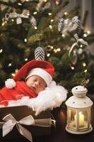 süßes neugeborenes baby mit weihnachtsmannmütze schläft in der weihnachtsgeschenkbox foto