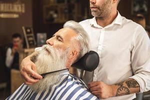 Schöner älterer Mann, der seinen Bart stylt und trimmt foto