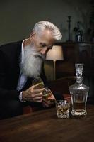 hübscher und bärtiger älterer Mann, der Whiskey trinkt foto