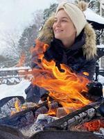 junge Frau, die sich an kalten Wintertagen an der Feuerstelle aufwärmt foto