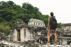 Frau mit Rucksack neben alten Maya-Ruinen foto