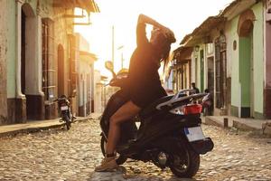 Frauenreisender, der Roller durch die alten Straßen der Stadt fährt foto