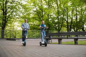 mutter und tochter fahren elektroroller im stadtpark foto