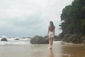 junge frau, die schönes weißes kleid trägt, posiert am strand foto