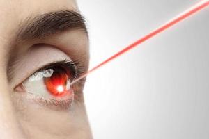 weibliches Auge mit einem Laserstrahl, der in die Iris zeigt foto