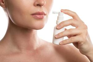 Frau verwendet Spray mit Analgetikum zur Linderung von Halsschmerzen foto