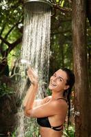 schöne Frau unter Dusche im Freien im tropischen Dschungel foto