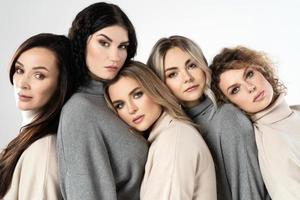 Gruppe verschiedener Frauen, die Rollkragenpullover auf grauem Hintergrund tragen foto