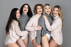 Gruppe verschiedener Frauen, die Rollkragenpullover auf grauem Hintergrund tragen foto