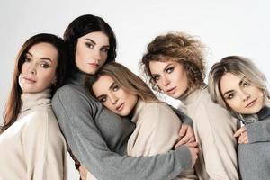 Gruppe verschiedener Frauen, die Rollkragenpullover auf grauem Hintergrund tragen foto