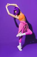 sorglose Tänzerin in farbenfroher Sportbekleidung vor violettem Hintergrund foto