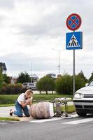 Schockierte Mutter auf dem Zebrastreifen nach einem Autounfall, als ein Fahrzeug ihren Kinderwagen trifft. foto