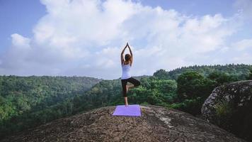 asiatische frauen entspannen sich im urlaub. spielen, wenn Yoga. auf der Bergfelsenklippe. Natur der Bergwälder in Thailand. junge Frau, die Yoga im weiblichen Glück der Natur praktiziert. übung yoga foto