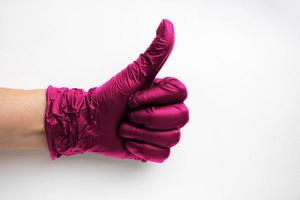 eine Hand in einem chirurgischen medizinischen Handschuh Farbe Viva Magenta, hervorgehoben auf weißem Hintergrund. Herstellung von Gummischutzhandschuhen.Hygiene- und Hygienestandards foto