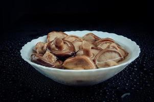 ein weißer Teller mit eingelegten Pilzen. Gesundes Dorfessen. eingelegter schwarzer Milchpilz. foto