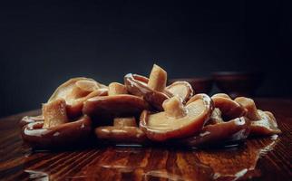 eine Streuung eingelegter Pilze auf einem Holztisch. Gesundes Dorfessen. eingelegter schwarzer Milchpilz. foto