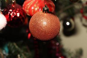Orangefarbene Glitzer-Weihnachtskugel, die in einem natürlichen Baum gefunden wurde foto