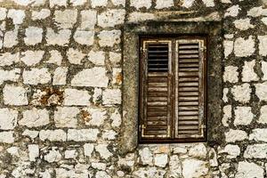 Steinmauer und Fenster mit geschlossenen Fensterläden aus Holz foto